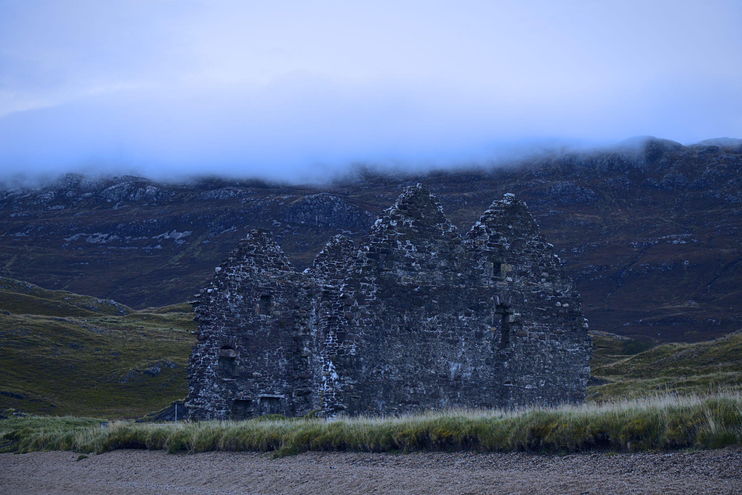 A ruined house below Loch Assynt in cool, misty dusk light